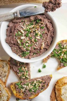 a white bowl filled with hummus next to sliced bread