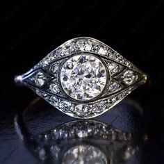 an antique style diamond ring on a black surface with reflection in the middle and side view