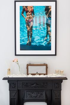 a painting hangs above a fireplace in a living room