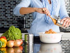 a woman is preparing food in the kitchen with vegetables on the counter and other ingredients