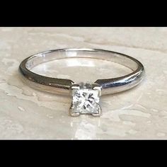 a white gold ring with a princess cut diamond