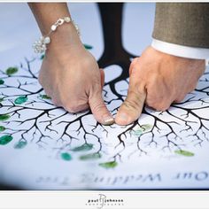 two people holding hands on top of a tree with leaves and branches painted on it