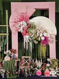 an arrangement of flowers and decorations in front of a pink wall with green drapes