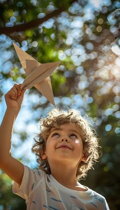 a young boy holding up a paper star