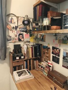 a desk with many books and pictures on the wall next to a book shelf full of books