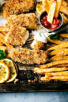 fried fish and fries on a tray with ketchup, lemon wedges and sauce