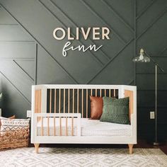 a baby's room with a white crib and gray walls, rugs and pillows