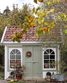 a small shed with windows and potted plants