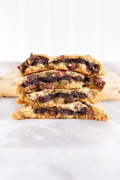 three cookies stacked on top of each other with chocolate chips and pecans in the background