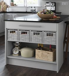 a kitchen island with baskets under it