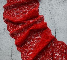 a red scarf is laying on the ground next to a white wall and cement floor