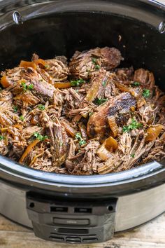 shredded beef and carrots in the slow cooker with parsley on top, ready to be cooked