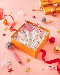 an orange box filled with personal care items on top of a pink surface next to christmas decorations