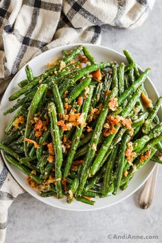 a white plate topped with green beans covered in seasoning and sprinkled with orange zest