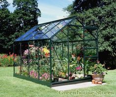 a green house that is in the middle of some flowers and plants on the ground