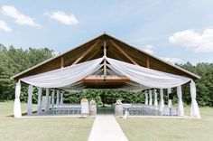 an outdoor wedding venue with white drapes and tables