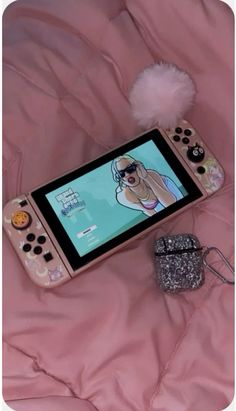 a nintendo wii game system sitting on top of a pink blanket next to a purse