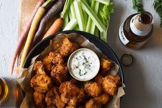 a plate full of fried food next to some vegetables and dips on a table