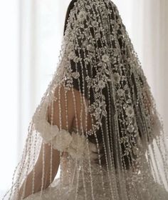 the back of a woman's wedding dress with beaded veil and flowers on it