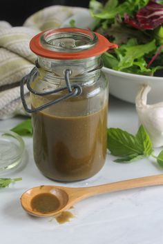 a jar filled with brown liquid next to a salad