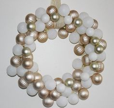 a wreath made out of white and gold ornaments hanging on a wall next to a door