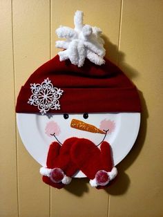 a plate with a snowman on it and a red hat hanging from the wall