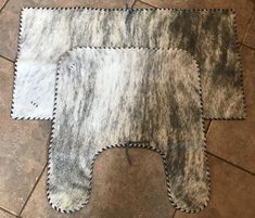 two sheepskin rugs are laying on the floor next to each other, one is gray and white