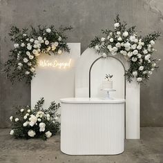 a white counter with flowers on it and a neon sign that says we are engaged