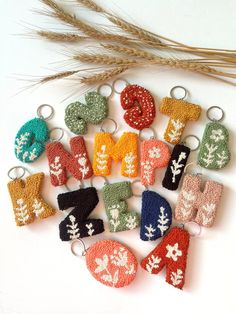 knitted mittens and gloves are arranged on a white surface next to wheat stalks