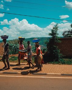 some people are walking down the street carrying baskets on their heads