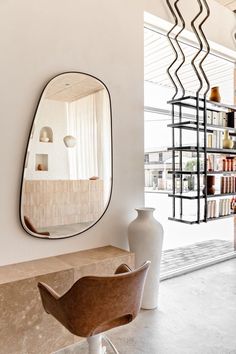 a room with a mirror, vase and bookshelf on the wall next to it