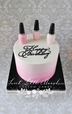 a cake decorated with three nail polish bottles on top of a black and white plate