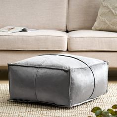 a silver square ottoman sitting on top of a rug