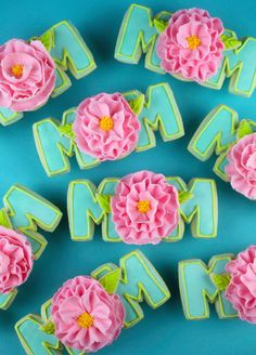 decorated cookies with pink flowers and the word mom spelled out in green icing on a blue background