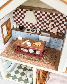 a dollhouse kitchen with blue cabinets and white counter tops is seen from the top