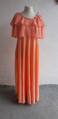 "Fab little 70s peach vintage cape dress maxi dress by Josh Charles with chiffon tiered cape neckline and bow detail, unlined and zipper to back back. Measurements are approximate and are taken laid flat, seam to seam, not on a model (Bust/chest/hip/waist are then doubled), please remember to leave yourself a little \"wiggle room\". Condition: Excellent - Ready to wear Modern Size Estimate: medium Mannequin Size:  UK 12 Label: Josh Charles Fabric:  Polyester Bust 36\" waist 30\" Shoulder to hem 56\" Hips: free\" I will post within 1-2 business days by 2nd class Royal Mail and I will combine postage when multiple items are purchased so please get in touch if that is the case. International customers please note that I send by Royal Mail so please get in touch for an accurate shipping cost. Peach Maxi Dress, Josh Charles, Peach Maxi Dresses, Peach Vintage, Yellow Striped Dress, Vintage Dress 80s, Vintage Cape, Dress 70s, 40s Fashion