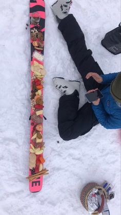 a man sitting in the snow next to his skis and some other things on the ground