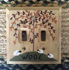 two light switch plates are decorated with trees and sheep in the middle, on top of a rug