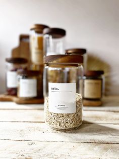 an open jar filled with seeds on top of a wooden table next to other jars