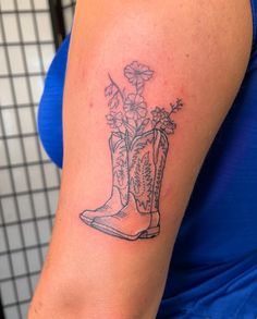 a woman with a tattoo on her arm has a boot and flowers in the boot