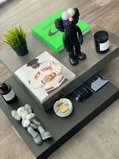 a coffee table with various items on it and a book in the background, sitting on a wooden floor