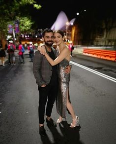 a man and woman are standing in the middle of an empty street at night time