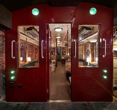 the inside of a train with red doors and green lights