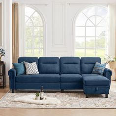 a living room with a blue sectional couch and pillows on the floor next to a large window