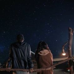 two people standing next to each other looking at the stars