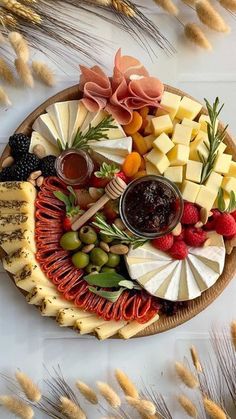 a platter with cheese, fruit and crackers on it next to wheat stalks