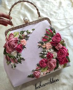 a handbag with flowers on it is being held by a woman's hand