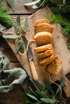 slices of bread sitting on top of a cutting board next to greenery and a knife