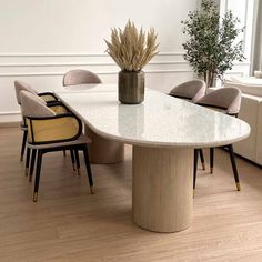 a dining room table with chairs and a vase filled with plants on top of it