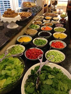 many bowls of salad are lined up on the counter